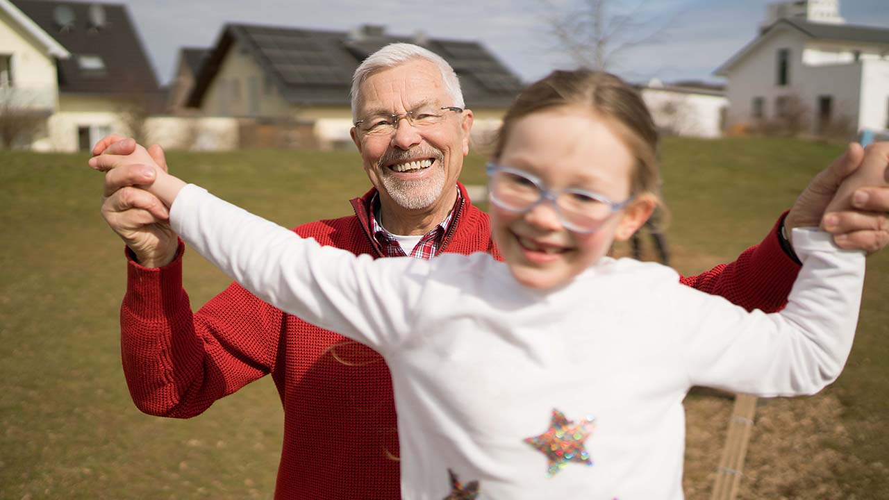Senior und Kind mit Brille lachen gemeinsam in der Natur