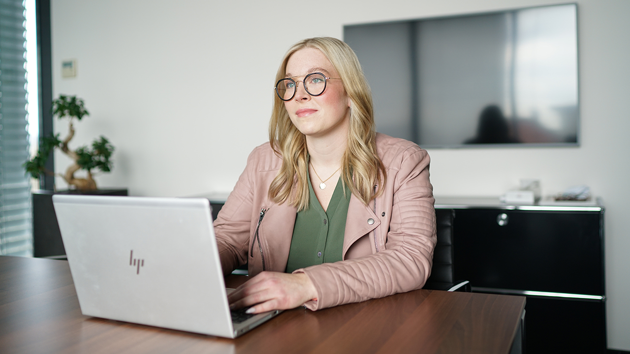 Frau mit Brille arbeitet an einem Laptop im Büro